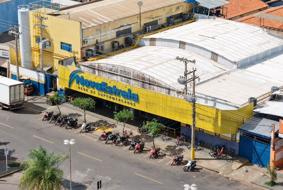 Fachada amarela do supermercado Nova Estrela com várias motos estacionadas em frente na rua.