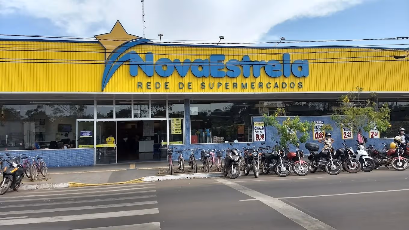 Fachada da rede de supermercados Nova Estrela com bicicletas e motos estacionadas em frente.